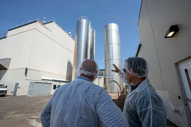 Organic Valley company officers Mark Pfeiffer and CEO Jeff Frank look at the huge storage tanks saved from the fire and new ones added in the reconstruction of the McMinnville plant. The company ordered additional tanks soon after the April 2021 blaze, which helped expedite rebuilding, allowing it to return to dry milk powder processing a year ago.